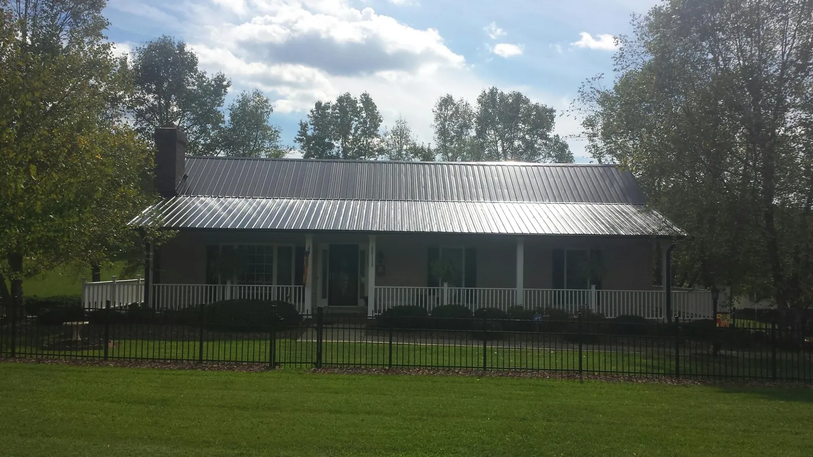 Gray metal roof on a brick ranch with a full width front porch — Gutter Guard Installation work by our crew in Donora