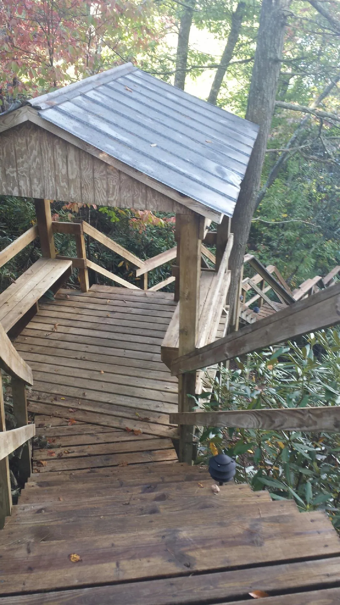 Metal roofed shelter over wooden steps on a wooded walkway — Skylight Repair & Installation work by our crew in Donora