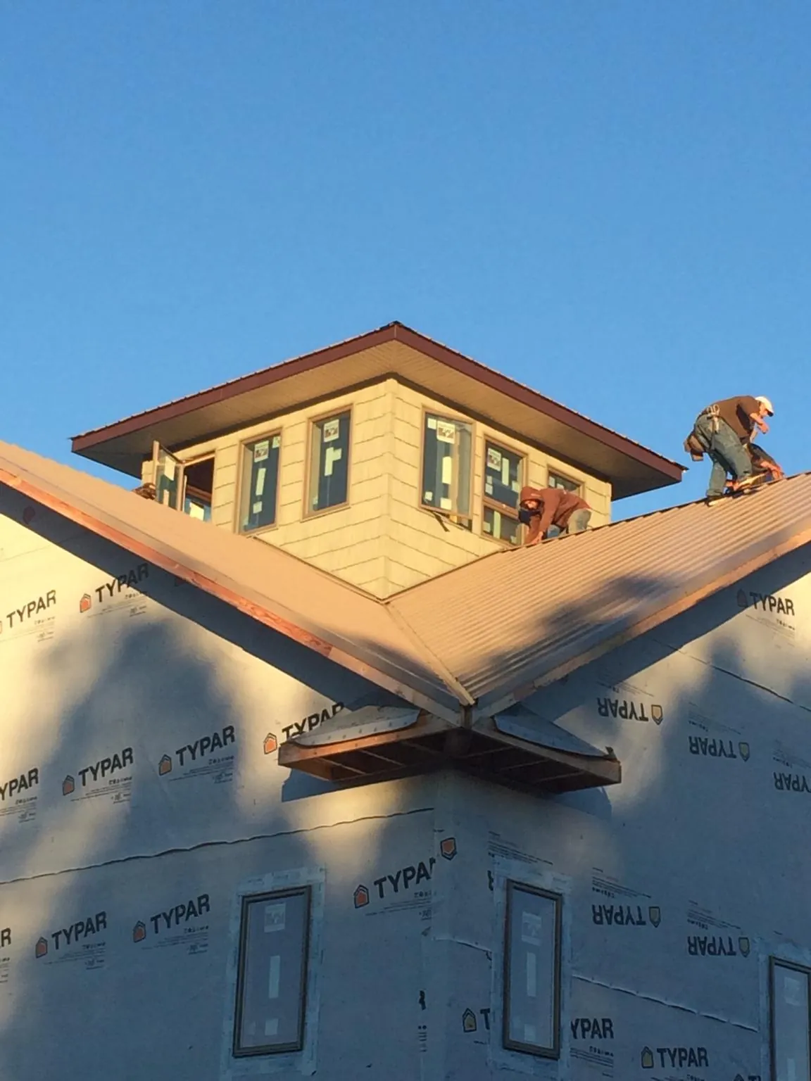 Roofers working around a rooftop cupola on a new metal roof at sunset — Roof Waterproofing in Donora by Roofing Brothers